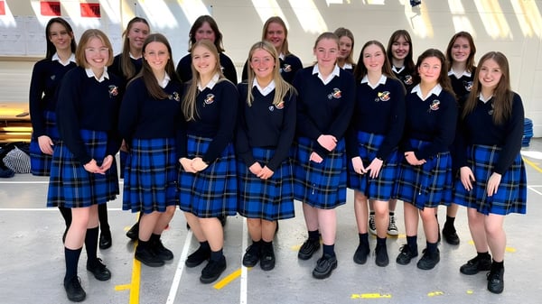 Un grupo de estudiantes de la St. Raphaela’s Secondary School posan juntas frente a un edificio con grandes ventanas.