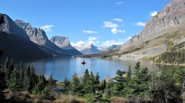 Un tranquilo lago de montaña con un pequeño bote y pinos en la orilla en el terreno de la St. Timothy High School.