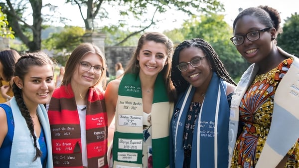 Un grupo de alumnas y alumnos está juntos al aire libre en el campus de St. Timothy's School frente a árboles y áreas verdes.