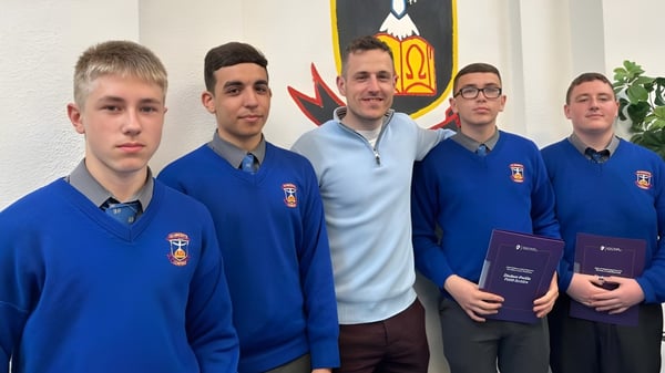 Un grupo de estudiantes de la St. Vincent's Secondary School en Dublín está frente a una pared con un escudo.