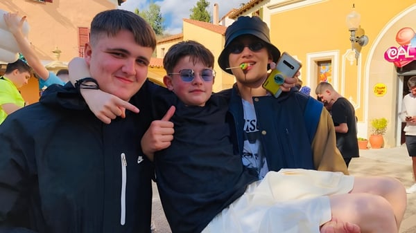 Tres estudiantes están en el patio exterior de la St. Vincent's Secondary School en Dublín frente a edificios coloridos.