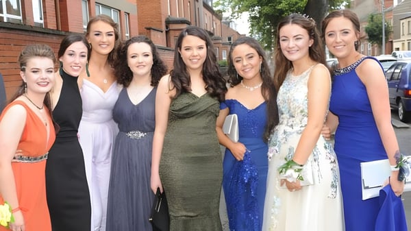 Un grupo de jóvenes mujeres vestidas de manera formal posan frente a un edificio de ladrillo en el campus de la St. Vincent's Secondary School.