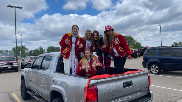 Un grupo de estudiantes en uniformes rojos está en la caja de un pickup en el terreno de St. Vrain Valley Schools.