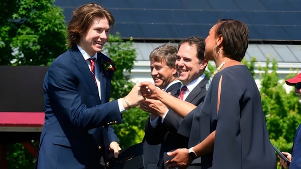 Un grupo de hombres en ropa formal se reúne en el jardín de la St. Anne's-Belfield School.