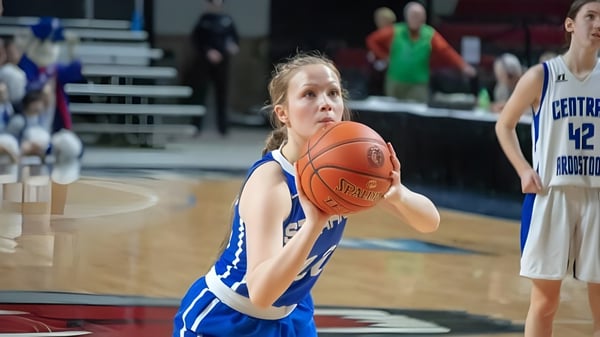 Una joven jugadora de baloncesto de la Stearns High School dribla el balón en la cancha de baloncesto.