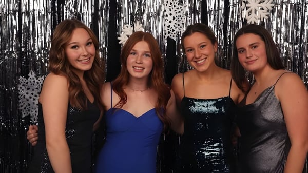 Cuatro estudiantes con cabello largo y oscuro posan frente a un fondo metálico en el campus de Stellys Secondary School.