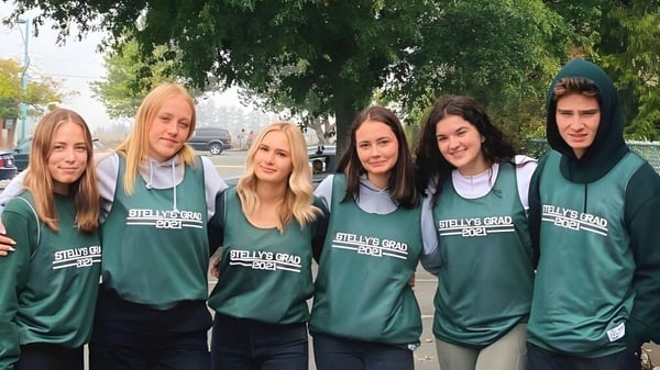 Un grupo de estudiantes de Stellys Secondary School está en camisetas verdes en el exterior frente a árboles y edificios.