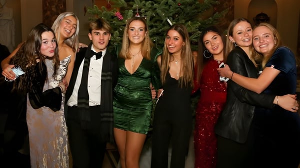 Estudiantes de la Stephen Perse Foundation posan en la fiesta de Navidad frente a un árbol decorado.