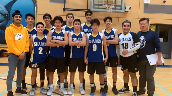 El equipo de baloncesto de la Steveston-London Secondary School está juntos en el gimnasio con uniformes a juego.