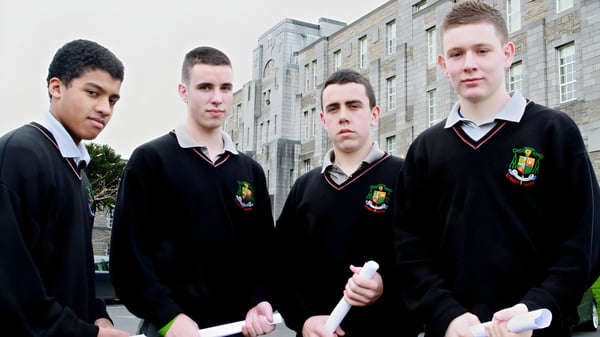 Cuatro alumnos en uniforme escolar están frente a un edificio de ladrillo en el campus de St. Mary’s College Ballysadare.