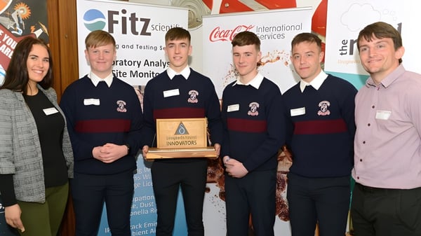 Estudiantes de la St. Mary’s Diocesan School sostienen un trofeo frente a un logo de Fitz y celebran su éxito en la competencia.