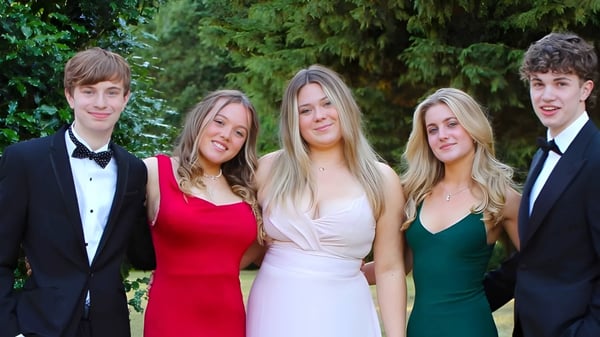 Un grupo de cinco jóvenes adultos en ropa formal posan en el bosque en el terreno del Stoke College.