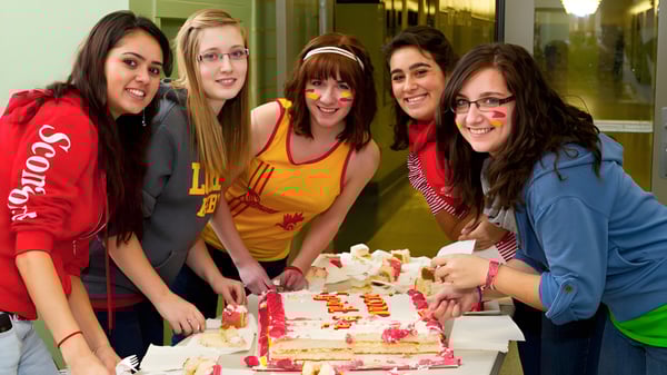 Un grupo de estudiantes de la Strathcona High School celebra junto con un pastel de cumpleaños en el interior.