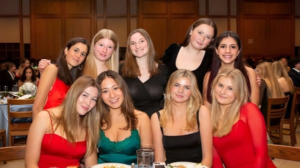 Un grupo de jóvenes mujeres vestidas de forma elegante posan juntas en un evento en la Suffield Academy.