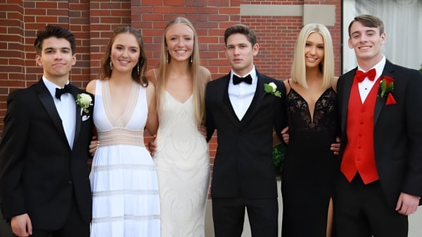Un grupo de personas en ropa formal posa frente a una pared de ladrillo en el campus de la Sugarloaf Senior High.