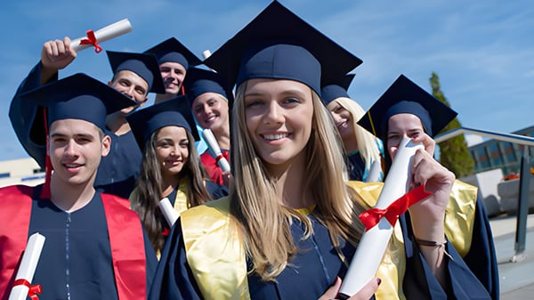 Un grupo de graduados de la Sunnybank State High School está junto en ropa académica sosteniendo sus diplomas en el campus escolar.