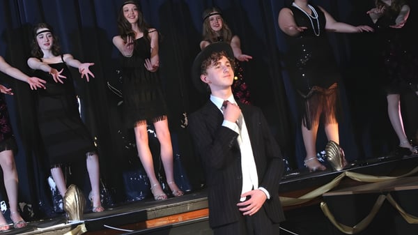 Un grupo de alumnas y alumnos está en el escenario de la Sutton Valence School frente a un telón oscuro.