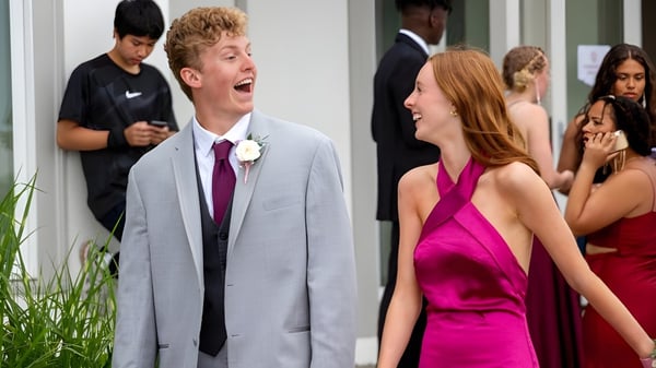 Una joven pareja está en un evento formal en el campus de Tabor Academy frente a un grupo de personas.