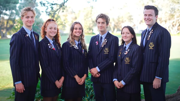 Un grupo de alumnos de la Takapuna Grammar School está reunido en un área parecida a un parque con árboles y zonas verdes.