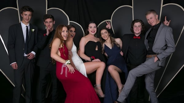 Un grupo de personas en ropa formal posando frente a un fondo abstracto en el campus de la Taradale High School.