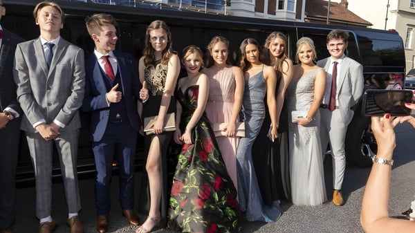 Un grupo de personas bien vestidas está de pie frente a un edificio en el campus de la Taunton School.