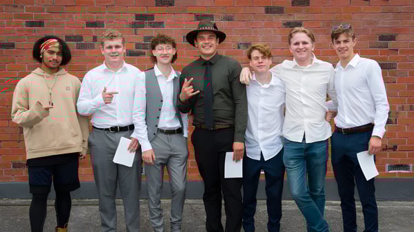 Un grupo de estudiantes está frente a una pared de ladrillo en el terreno del Taupo-nui-a-Tia College.