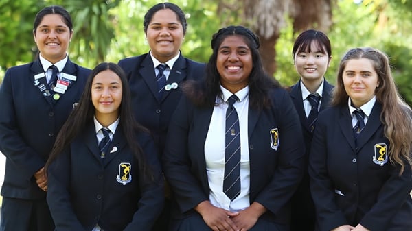 Un grupo de estudiantes en uniformes escolares está junto en un área verde al aire libre de Tauranga Girl´s College.