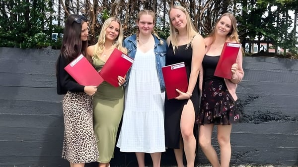 Un grupo de jóvenes estudiantes está de pie frente a una cerca de madera en el área verde de la Te Puke High School.