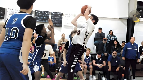 Se está llevando a cabo un partido de baloncesto en la cancha de la Teays Valley Christian School con jugadores de ambos equipos y espectadores de fondo.
