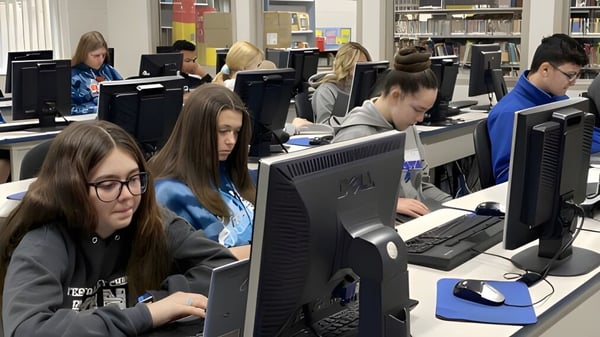 Estudiantes de la Teays Valley Christian School trabajan en computadoras en el aula con libros y materiales de enseñanza de fondo.