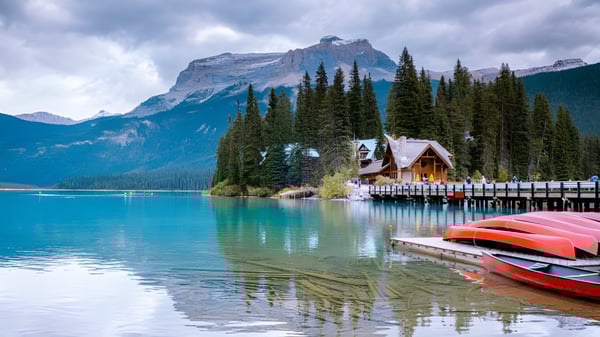 Un tranquilo lago alpino con canoas de colores en un muelle de madera, rodeado de montañas y bosques de pinos, cerca de la Technical Vocational High School.