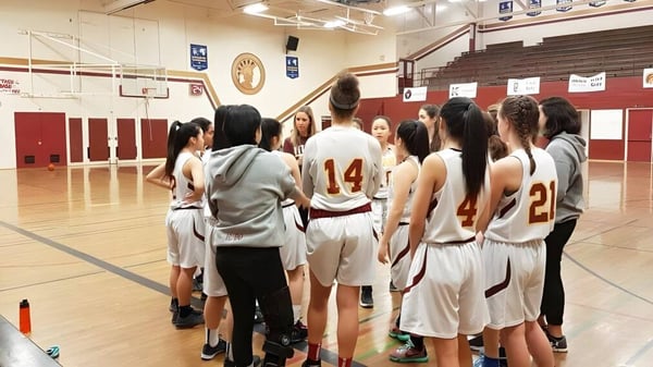 Un grupo de jóvenes jugadoras y jugadores de baloncesto entrenan en el gimnasio de la Templeton Secondary School.