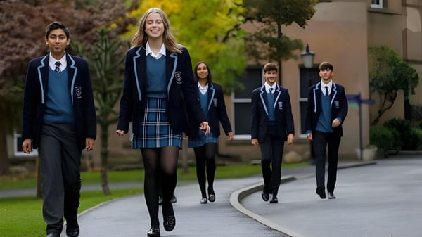Un grupo de estudiantes en uniformes escolares camina junto en un camino rodeado de verde en el campus de Tettenhall College.