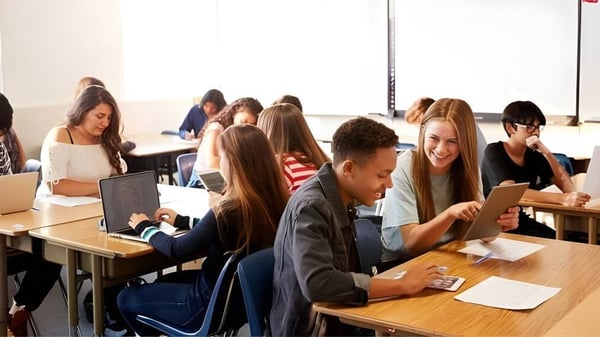 Un grupo de estudiantes de The Barnes Academy está sentado en un aula y trabaja juntos en diferentes tareas.
