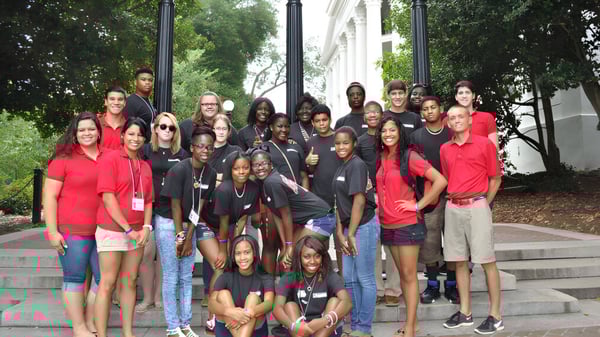 Un grupo de estudiantes se reúne en escaleras exteriores frente a un edificio con columnas en el campus de The Barnes Academy.