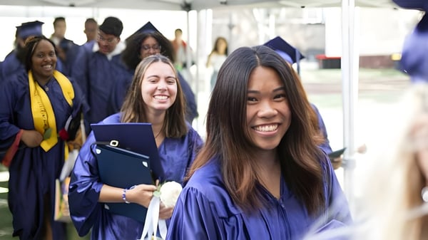 Un grupo de graduados de The Beekman School celebra juntos su graduación en togas azules.