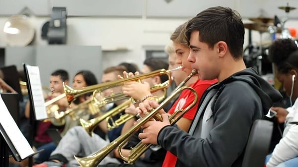 Estudiantes de The Beekman School tocan instrumentos de metal frente a equipo musical.