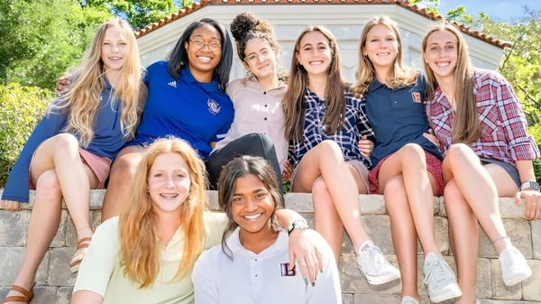 Un grupo de alumnas está sentada en las escaleras frente a un edificio de The Bolles School.