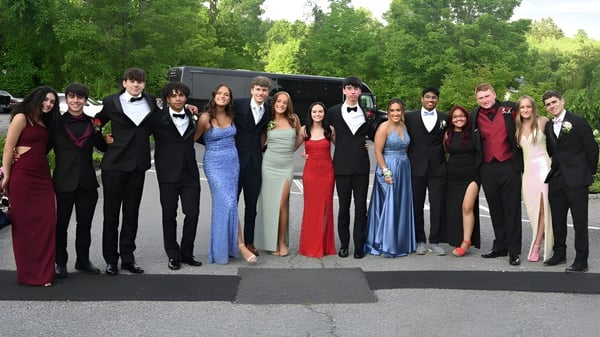 Un grupo de personas vestidas elegantemente está de pie juntas en el área verde del campus de The Bolles School.