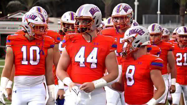 Un equipo de fútbol de The Bolles School está junto en el campo de juego con un estadio de fondo.