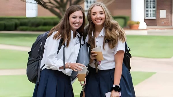 Dos estudiantes de The Brook Hill School están juntas al aire libre frente a un edificio de ladrillo.