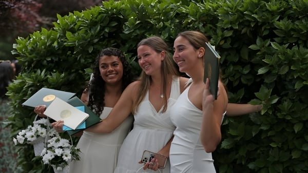Tres alumnas de The Bryn Mawr School están juntas en un terreno de jardín verde.