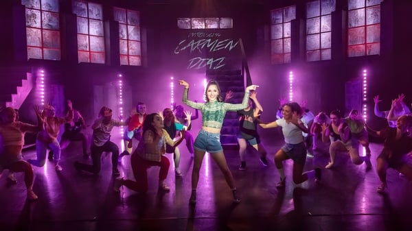 Una actuación de danza en el escenario de The Hammond School con bailarines vibrantes y luz de escenario violeta.