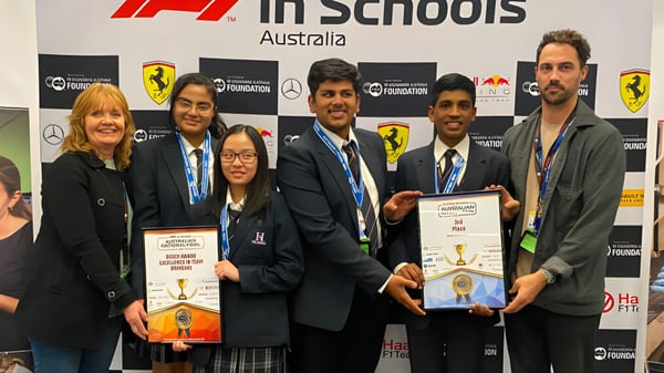 Estudiantes y adultos de The Heights School están juntos en la entrega de premios F1 in Schools frente a un fondo de logo.