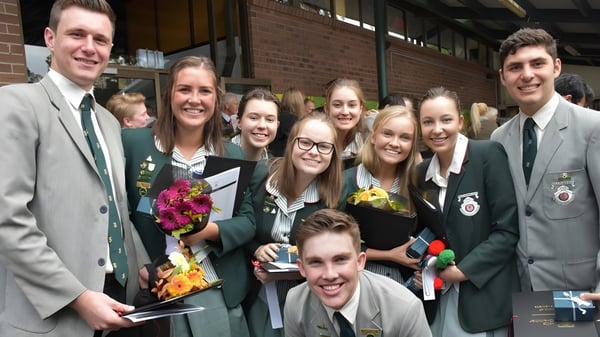 Un grupo de estudiantes de The Hills Grammar School posan frente a un edificio de ladrillo para una foto.