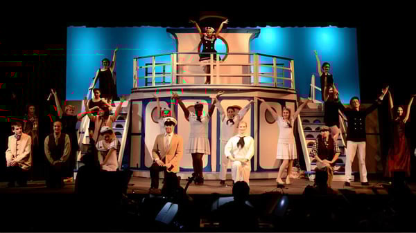 Un gran grupo de estudiantes de The Hun School of Princeton presenta una actuación en una plataforma de escenario.