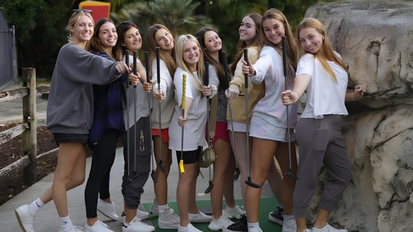 Un grupo de estudiantes se encuentra juntos afuera frente a un fondo rocoso en el campus de The King's Academy.