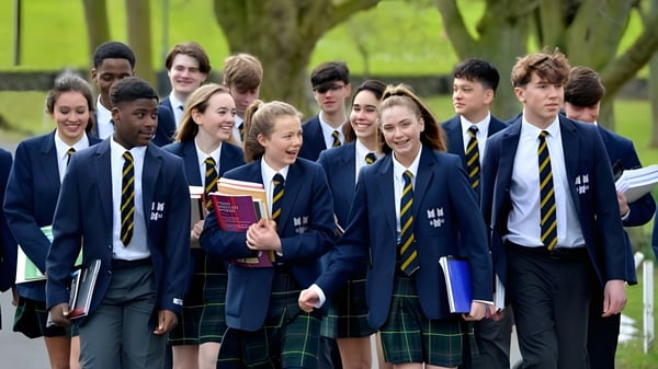 Un grupo de estudiantes de The Kings Hospital camina por un camino rodeado de naturaleza verde.
