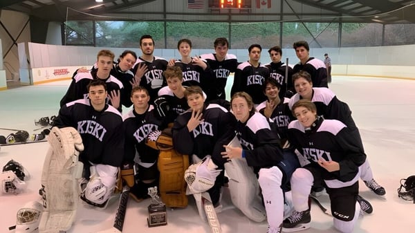 Un grupo de estudiantes de The Kiski School posan en uniformes de hockey sobre la pista de hielo.