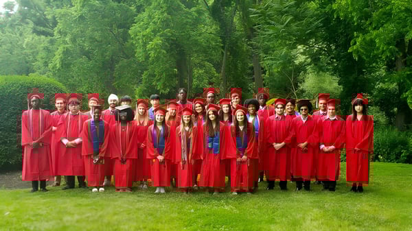 Un grupo de graduados de The Knox School está al aire libre entre árboles verdes.